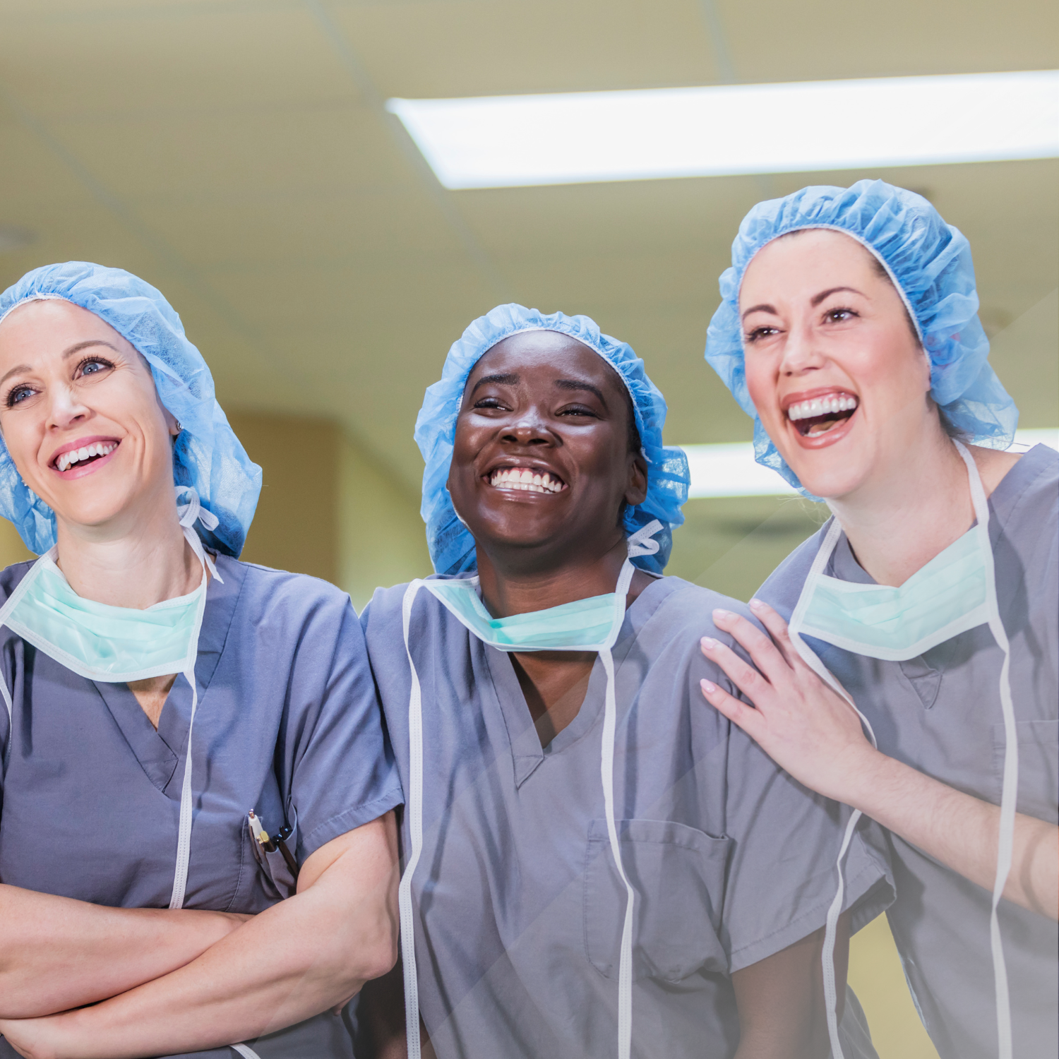 Healthcare workers laughing in a group of 3 while wearing surgery garments.