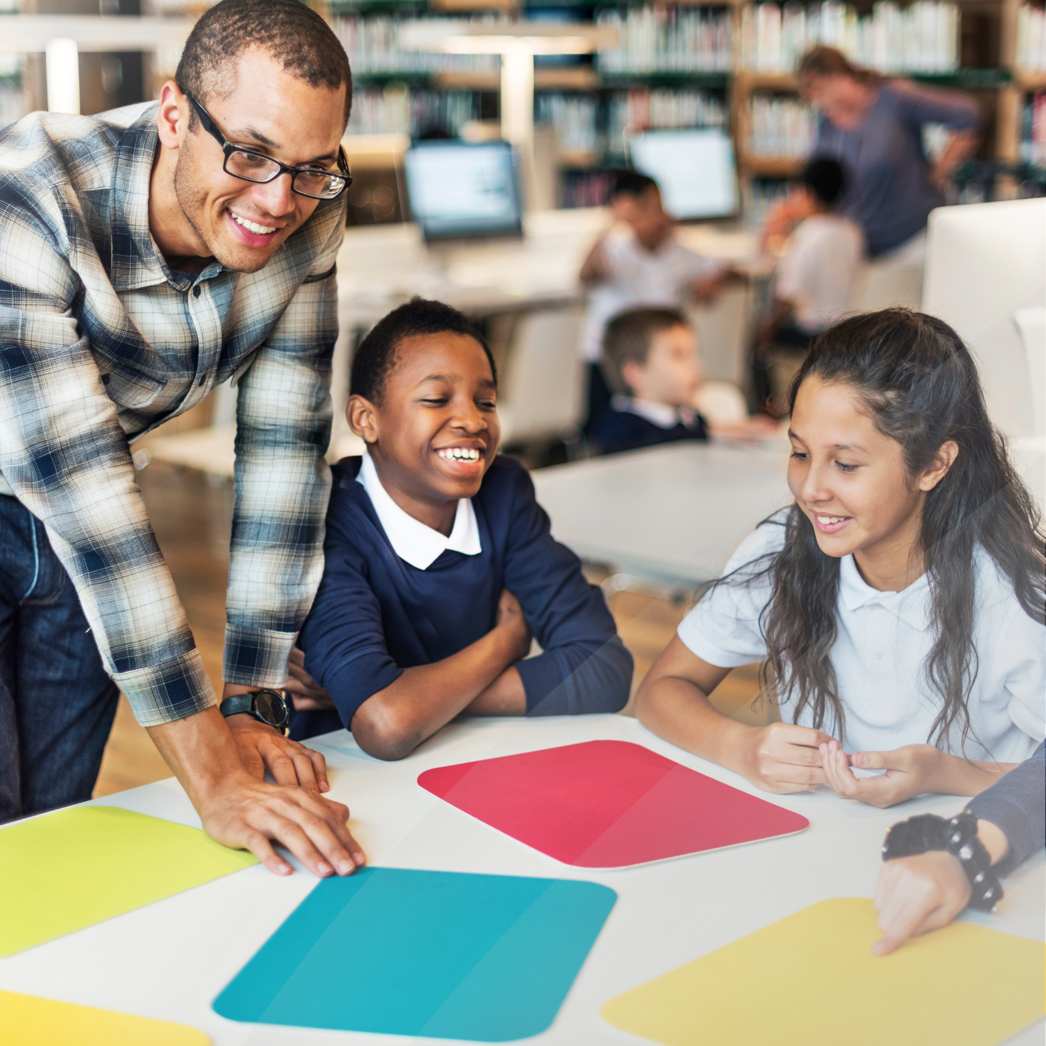 Teacher smiling and leaning over a desk to help students.